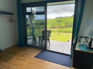a kitchen with a door open to a deck with a table at Bungalow Tiny House Puunui 