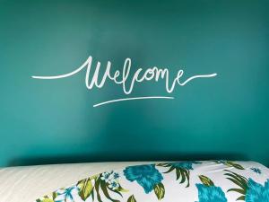 a blue wall with the word welcome written on top of a bed at Bungalow Tiny House Puunui 