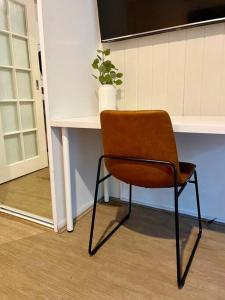 柏斯的住宿－A city oasis - cozy 1 bed apartment，一张棕色椅子,坐在桌子旁,种植植物