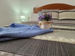 un letto con una coperta e un vaso con fiori viola di Casa Rural La Replaceta a Chulilla