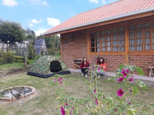 two women sitting in front of a building with a tent at Cabañas Tecla María in Otavalo