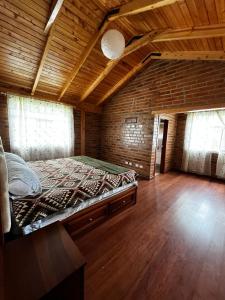 Cama grande en habitación con techo de madera en Cabañas Tecla María, en Otavalo