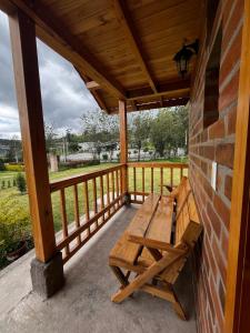 - un banc en bois sur la terrasse couverte d'une maison dans l'établissement Cabañas Tecla María, à Otavalo