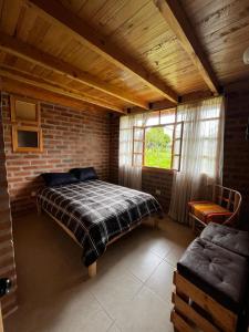 - une chambre avec un lit et un mur en briques dans l'établissement Cabañas Tecla María, à Otavalo