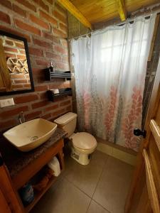 y baño con aseo y lavamanos. en Cabañas Tecla María, en Otavalo