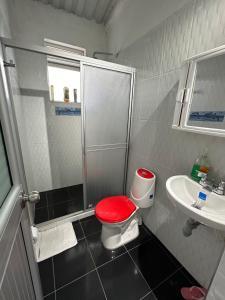 ein Badezimmer mit einem roten WC und einem Waschbecken in der Unterkunft Finca las marias in Tena