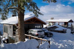 a house with a car parked in the snow at Cedar Lodges Resort and Residences Galiyat in Chhāngla Gali