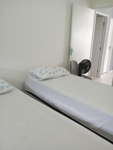Bett in einem Zimmer mit weißer Bettwäsche und Kissen in der Unterkunft Casatriz in Paripueira