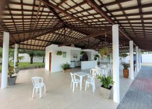eine Terrasse mit weißen Stühlen und Tischen sowie einer Holzdecke in der Unterkunft Casatriz in Paripueira