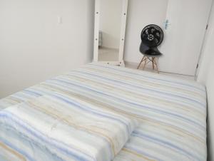ein Bett mit einer gestreiften Decke und einem Ventilator in der Unterkunft Casatriz in Paripueira