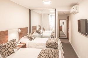 a hotel room with two beds and a television at Palm Beach Plaza Hotel in Montevideo