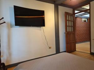 um quarto com uma cama e uma televisão de ecrã plano na parede em Casa Vélez: habitación natural em Villamaría