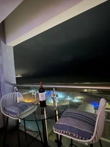 a glass table with a bottle of wine and two chairs at Departamento con vista al mar in Lima
