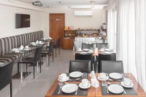 a dining room with tables and chairs and a kitchen at Palm Beach Plaza Hotel in Montevideo