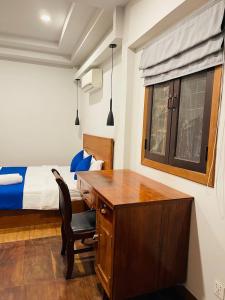 a bedroom with a desk and a bed with a window at Roya Khmer House in Siem Reap