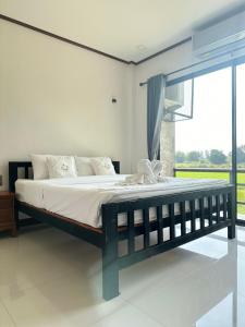 a large bed in a bedroom with a large window at Ban Suweena in Uthai Thani