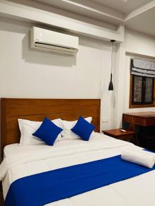 um quarto com uma cama branca e almofadas azuis em Roya Khmer House em Siem Reap