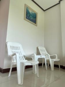 3 sillas blancas y una mesa en una habitación en Ban Suweena, en Uthai Thani