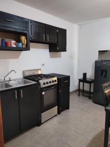 uma cozinha com armários pretos, um fogão e um lavatório em Mi casa em Ciudad Juárez