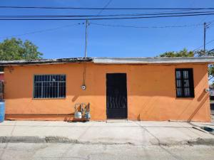 an orange building with a black door on a street at Mi casa in Ciudad Juárez