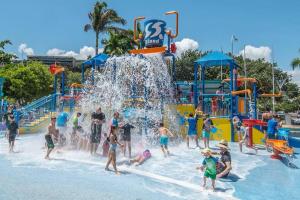 a group of people playing in a water park at NEW! 2BR Beachside Boutique Living in Townsville in Townsville