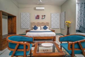 1 Schlafzimmer mit einem Bett und 2 Stühlen in der Unterkunft MERAKI VILLA - 5 BR Luxury Villa with private pool in Udaipur