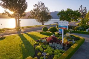 um sinal num jardim ao lado de um lago em Radfords on the Lake em Te Anau