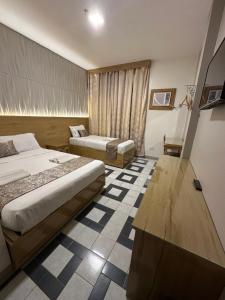 Habitación de hotel con 2 camas y escritorio en Bamboo Garden Bussiness Inn, en Dipólog
