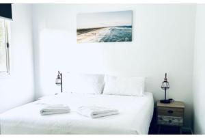 Una cama blanca con dos toallas blancas. en Discovery Parks - Narooma Beach, en Narooma