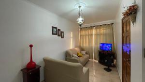 ein Wohnzimmer mit einem Sofa und einem TV in der Unterkunft Desativado in São Vicente