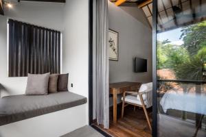 a bedroom with a bed and a desk and a window at Villa Sessun by Alfred in Bali in Canggu