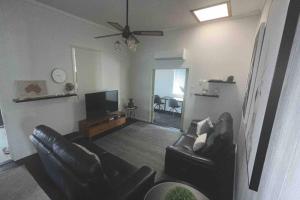 a living room with black leather furniture and a flat screen tv at Cottage on the Bay 