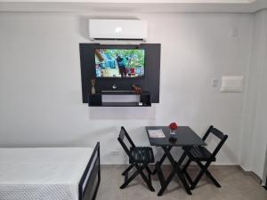 a room with a table and a tv on a wall at Condomínio Inn The Studio in Foz do Iguaçu