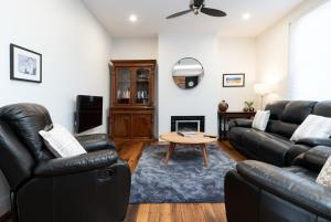 a living room with black leather furniture and a table at Gorgeous on Gleadow: The Twin in Invermay