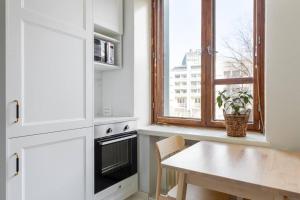 a kitchen with white cabinets and a table and a window at Charming suite with garden views steps from metro in Helsinki