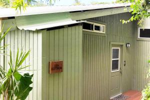 ein grünes Haus mit einem Schild an der Seite in der Unterkunft PonoMana Oasis's - Zen Cottage in Captain Cook