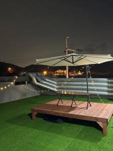stół piknikowy z parasolem na polu trawy w obiekcie Jinistay #Netflix #Oceanview #private barbeque facility #1pm checkout w mieście Ulsan