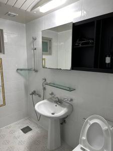 ein weißes Badezimmer mit einem Waschbecken und einem Spiegel in der Unterkunft Jinistay #Netflix #Oceanview #private barbeque facility #1pm checkout in Ulsan