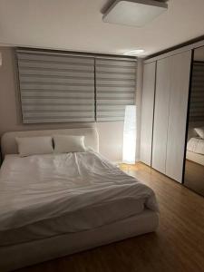 1 dormitorio con 1 cama blanca en una habitación en Jinistay #Netflix #Oceanview #private barbeque facility #1pm checkout en Ulsan