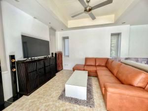 a living room with a brown leather couch and a flat screen tv at Lakeview Pool Villa Near Beautiful Beach VCS1 in Phuket Town