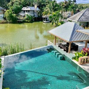 a swimming pool next to a body of water at Lakeview Pool Villa Near Beautiful Beach VCS1 in Phuket Town
