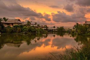 un coucher de soleil sur une étendue d'eau avec des maisons dans l'établissement Lakeview Pool Villa Near Beautiful Beach VCS1, à Phuket