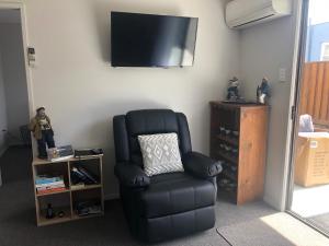 a room with a chair and a television on a wall at #5 on Blenheim St in Renwick