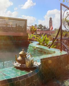 eine Teekanne auf einem Tisch neben einem Brunnen in der Unterkunft Riad Persephone in Marrakesch