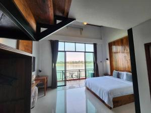 a bedroom with a bed and a view of the water at Suksomboonhotel in Loei