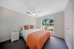 a white bedroom with a bed and a window at Discover Mount Annan - Spacious 6-BR House in Narellan