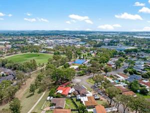 une vue aérienne sur une ville avec des maisons et des arbres dans l'établissement Discover Mount Annan - Spacious 6-BR House, à Narellan