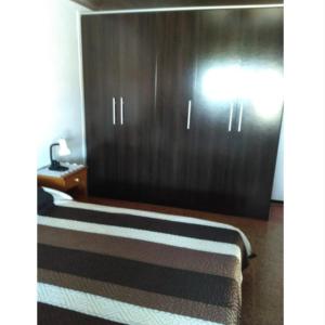 1 dormitorio con 1 cama y armario de madera en Lo de Sandra, en Costa Azul