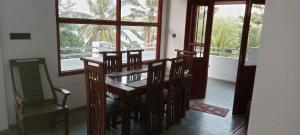 a dining room with a table and chairs and windows at The Green Lagoon Villa in Hikkaduwa