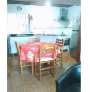 eine Küche mit einem Tisch und Stühlen mit einem roten Tischtuch in der Unterkunft Lo de Sandra in Costa Azul